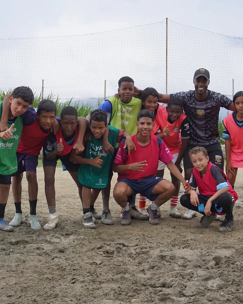 Un entrenador de 11 Cracks celebra junto a un equipo de niños y niñas en una cancha de barrio.