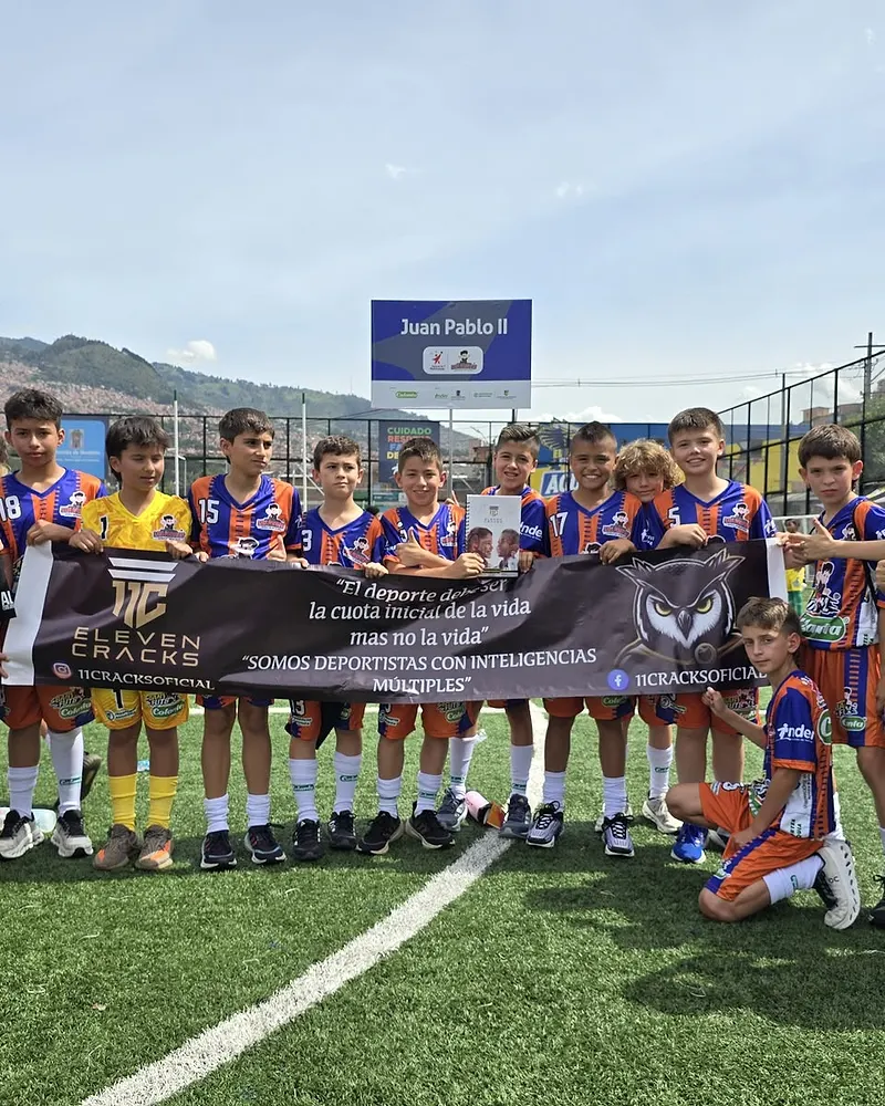 Equipo juvenil de un club afiliado sosteniendo el pendón de 11 Cracks en un torneo real.