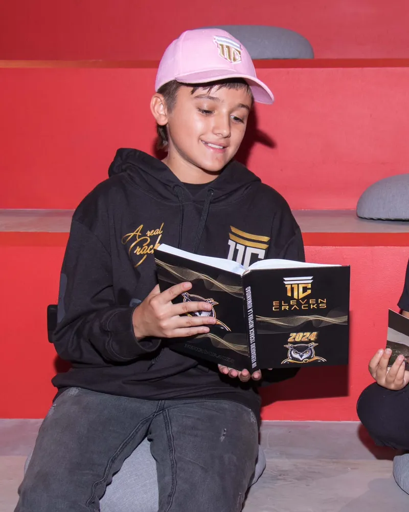 Dos deportistas jóvenes leen juntos el anuario 11 Cracks 2024.