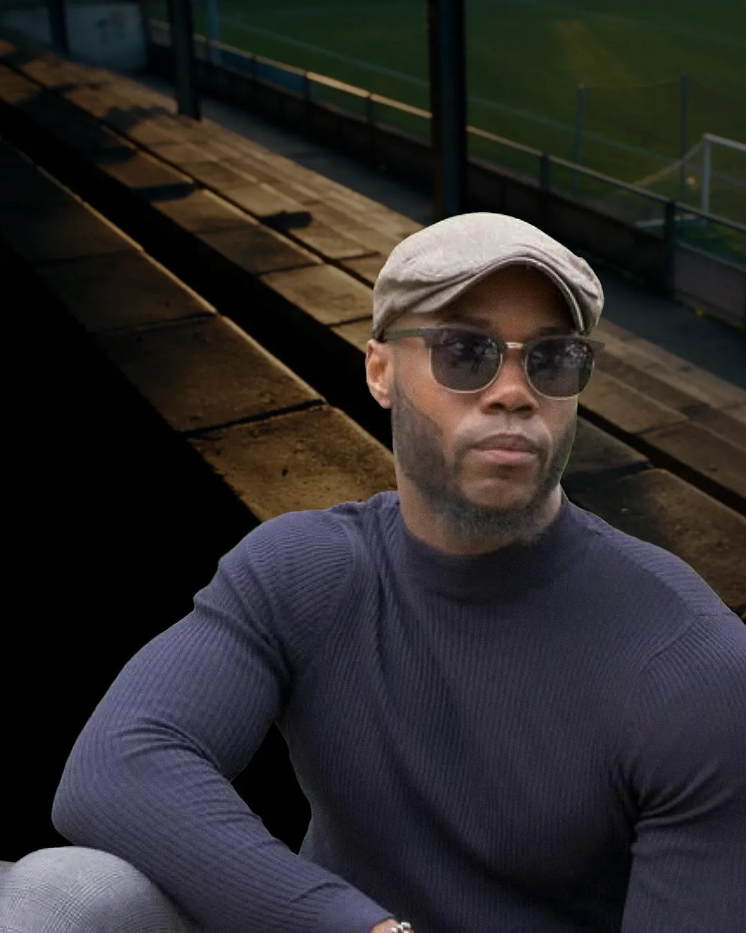 Víctor Córdoba, CEO de 11 Cracks, con gorra y lentes de sol, en una grada de cancha.