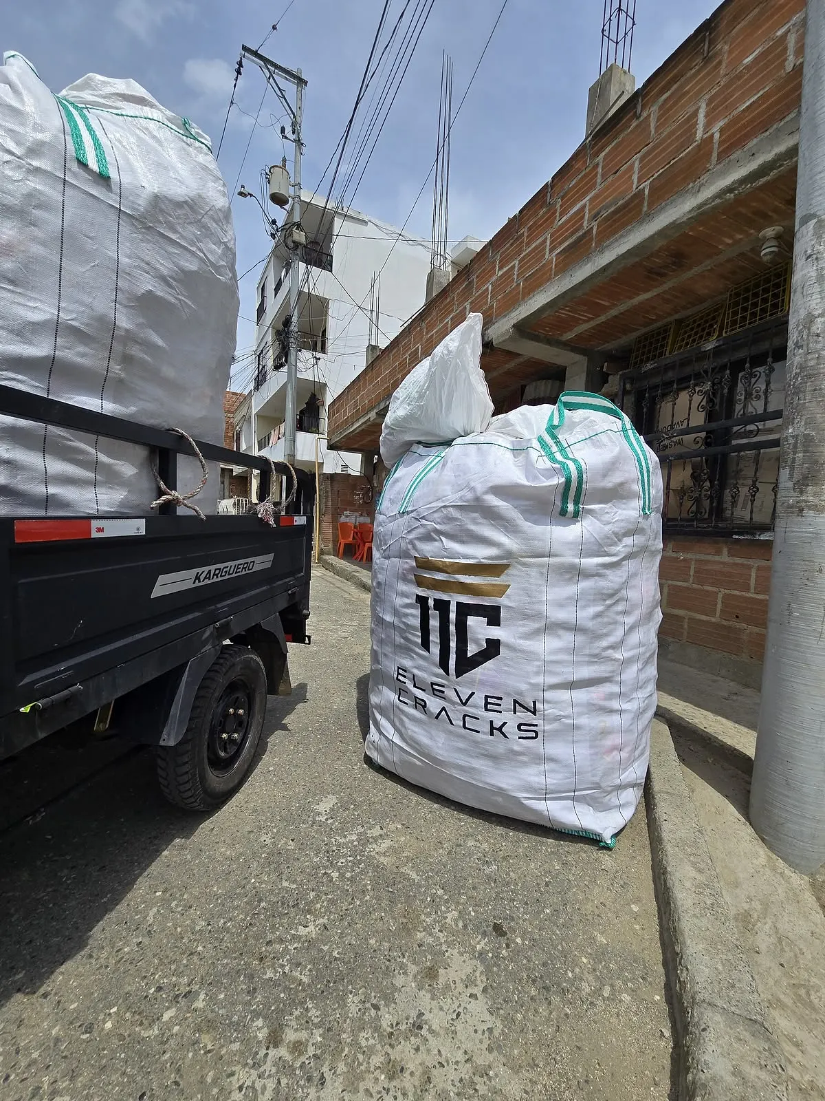 Un costal de recolección PET con el logo de 11 Cracks, listo para ser transportado en un barrio.