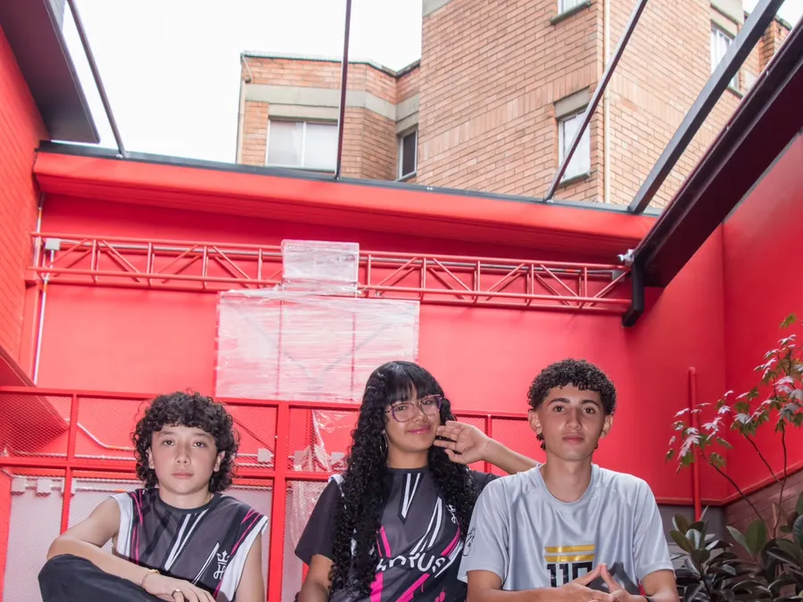 Tres jóvenes de 11 Cracks posan junto a cajas de madera con frases del club.